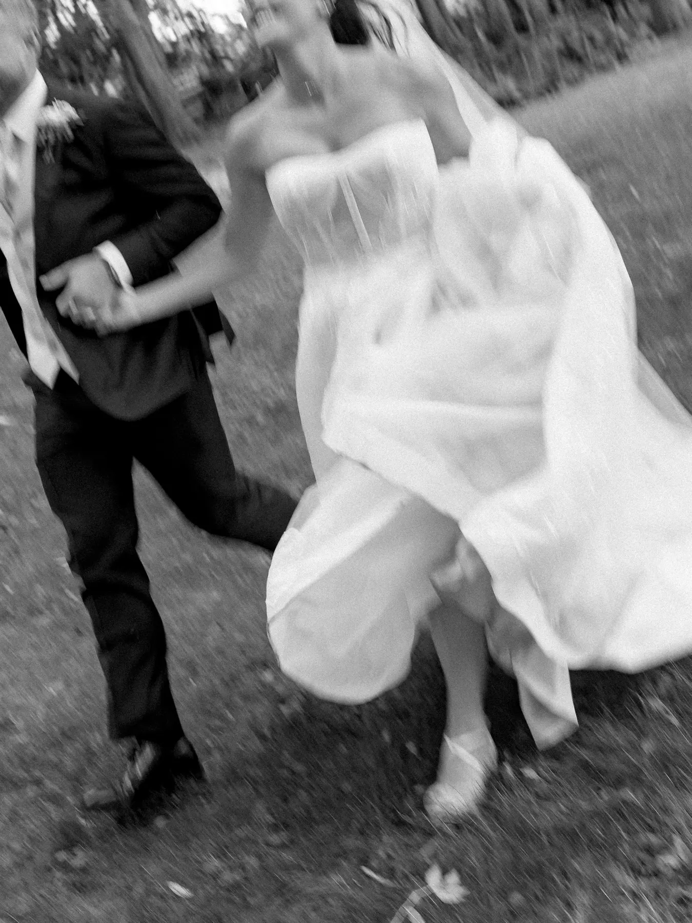 A bride and groom mid-step, caught in a blurred black-and-white frame.